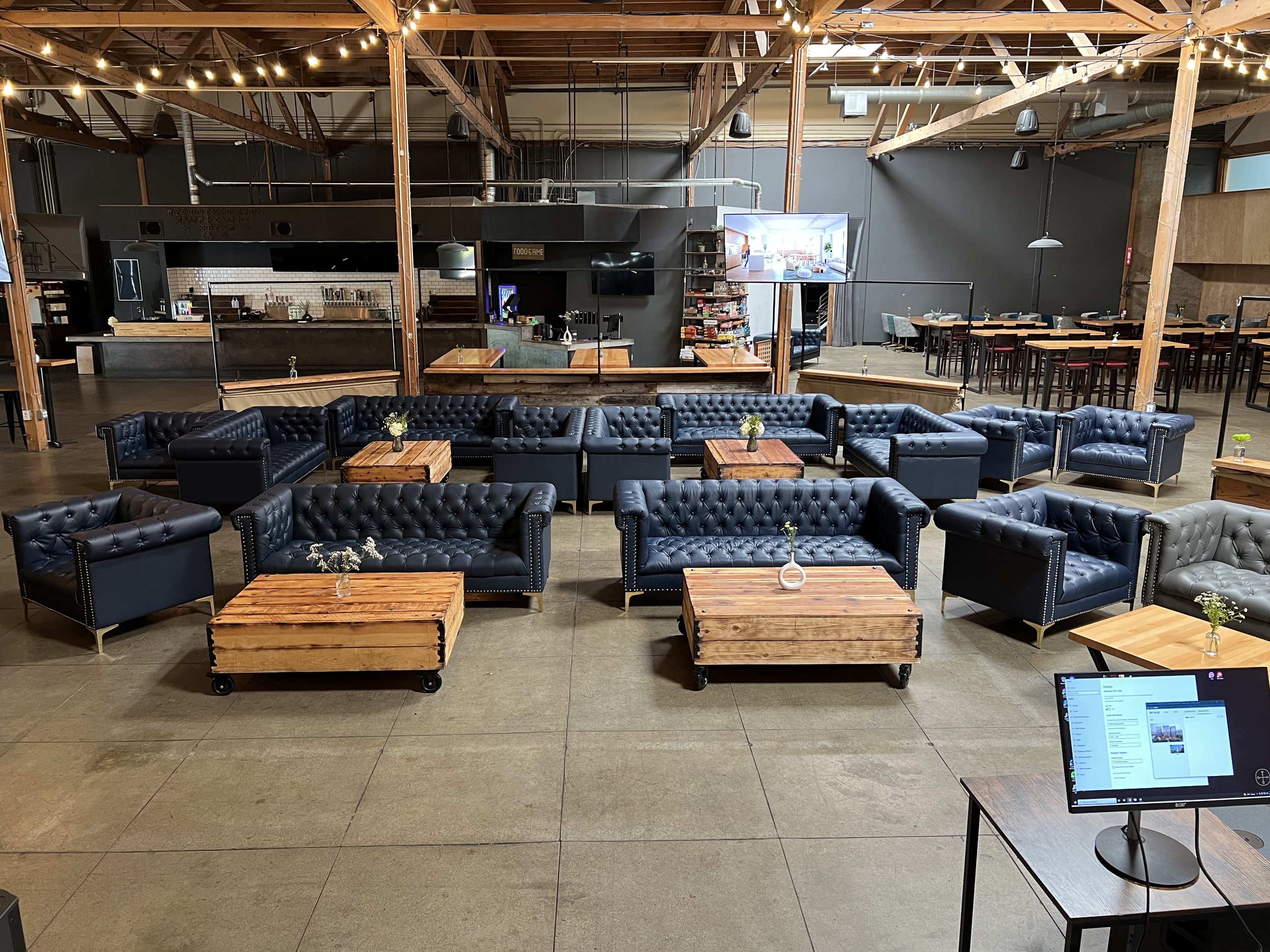 Warm lounge seating beneath timber beams and string lights inside Guildhouse